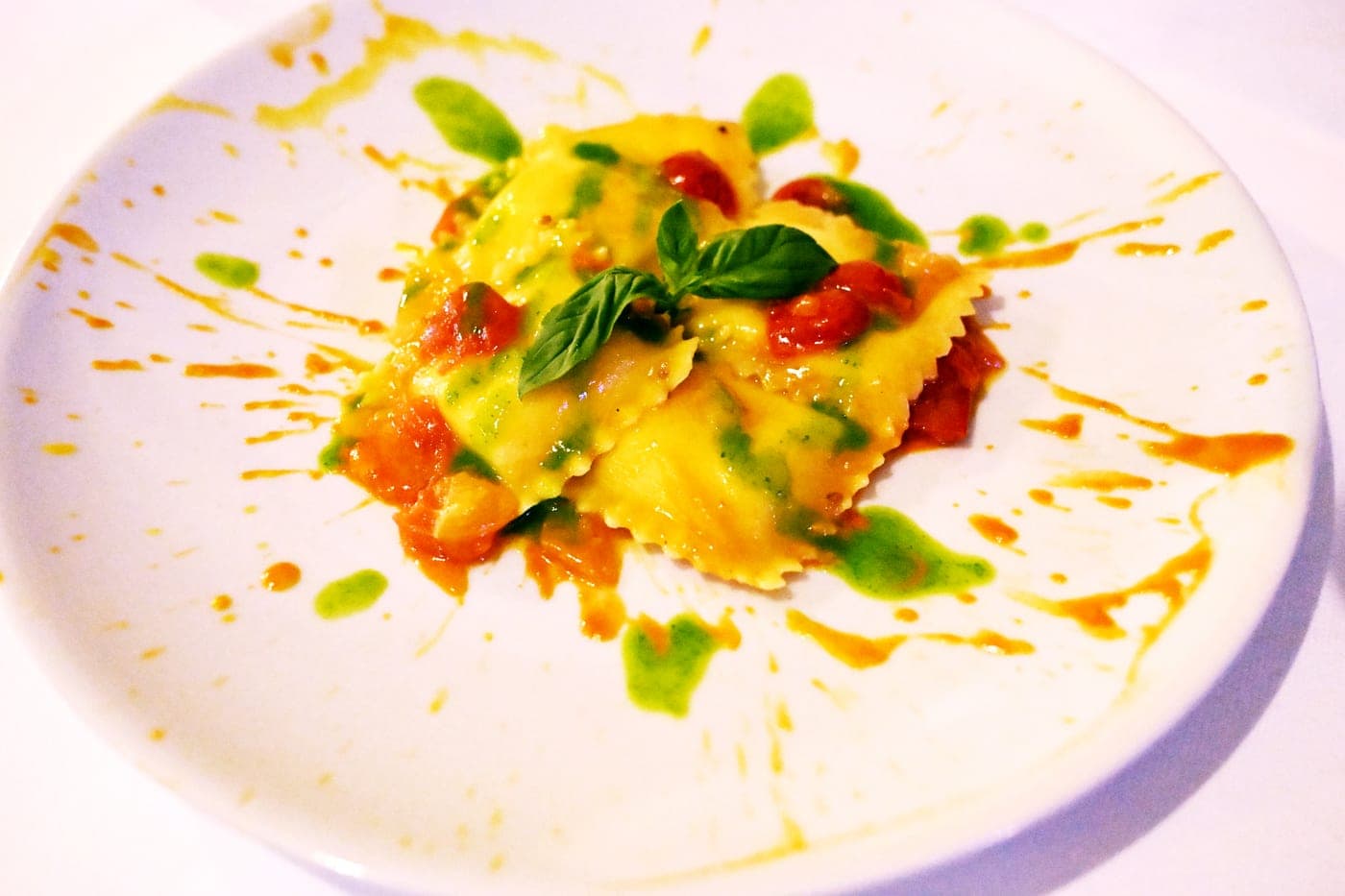 Ravioli impiattati con decorazione di salsa al basilico